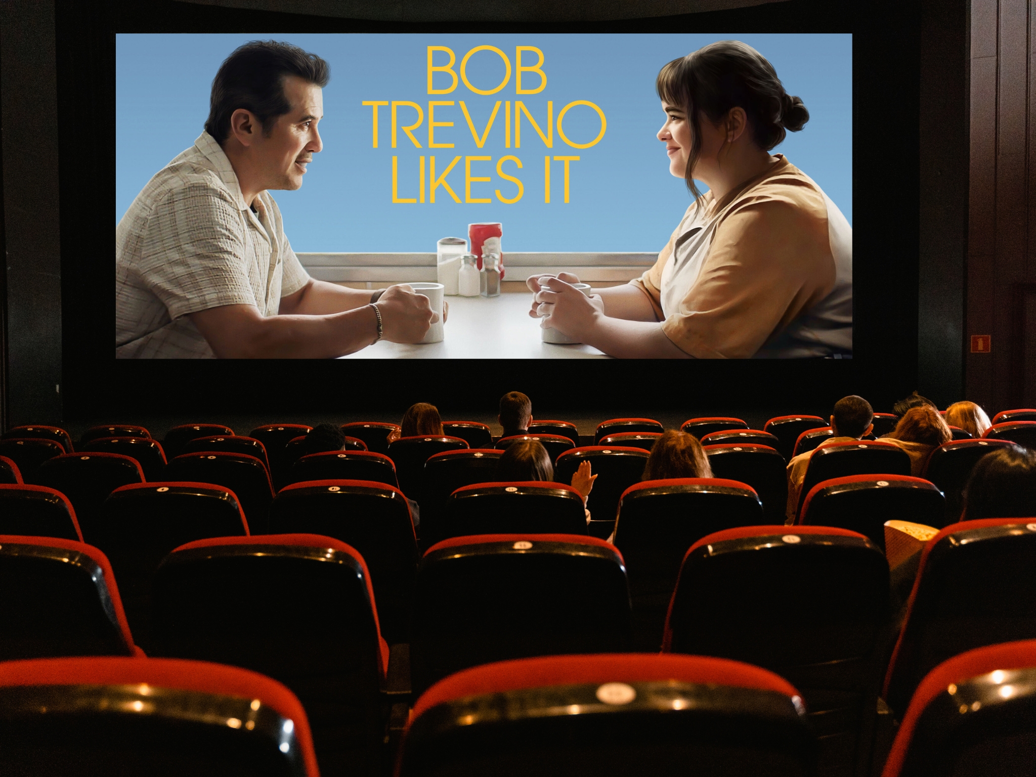 A crowded movie theater filled with audience members seated in red chairs, enjoying a film under dim lighting